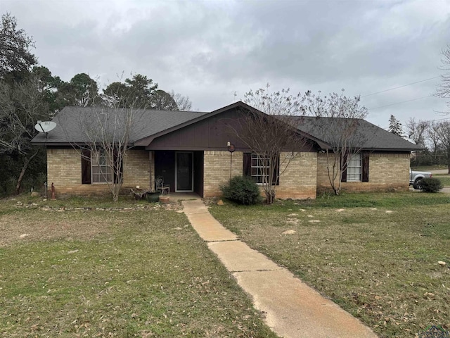 ranch-style house featuring a front yard, brick siding, and roof with shingles