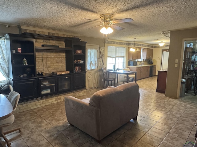 living room with a textured ceiling, dark tile patterned flooring, ornamental molding, and ceiling fan