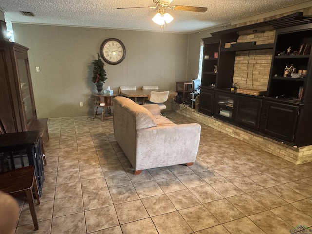 living area featuring ceiling fan, visible vents, a textured ceiling, and light tile patterned flooring