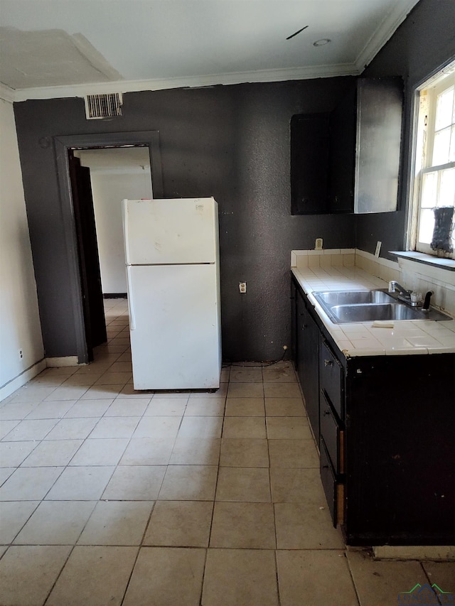 kitchen featuring sink, white fridge, light tile patterned floors, and ornamental molding