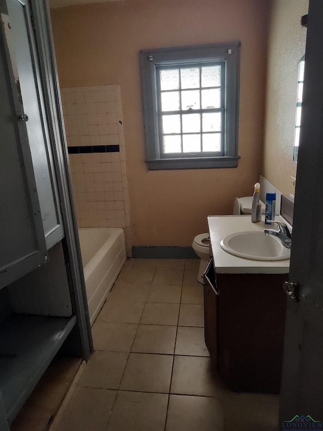 bathroom featuring tile patterned floors, vanity, toilet, and a bathing tub