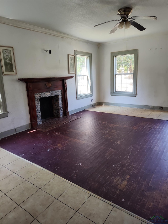 unfurnished living room featuring a high end fireplace, light tile patterned floors, ceiling fan, and crown molding