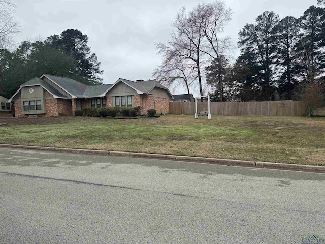 exterior space featuring a front yard, brick siding, and fence