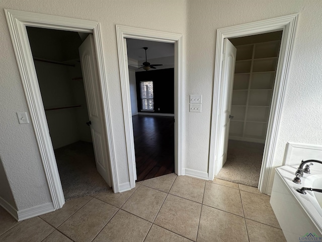 interior space featuring tile patterned flooring, ceiling fan, and a tub to relax in