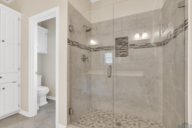 bathroom with tile patterned floors, toilet, and a shower with door