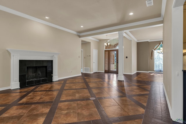 unfurnished living room featuring a tiled fireplace, crown molding, dark tile patterned floors, and a notable chandelier