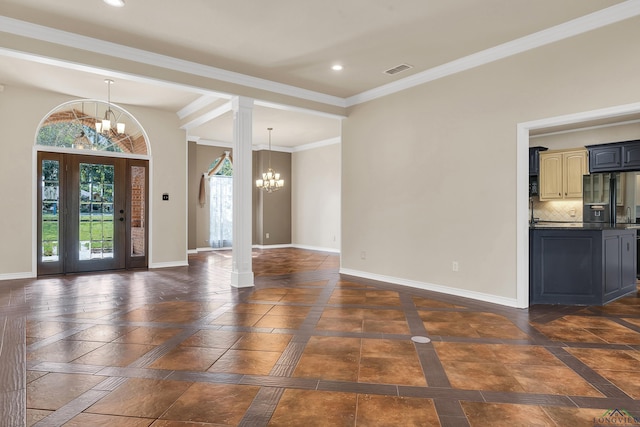 entrance foyer with ornate columns, ornamental molding, and an inviting chandelier