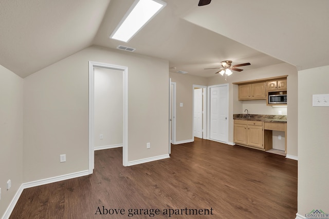 kitchen featuring light brown cabinets, stainless steel microwave, lofted ceiling, dark wood-type flooring, and ceiling fan