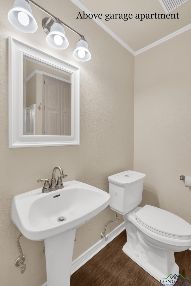 bathroom featuring wood-type flooring, toilet, and crown molding