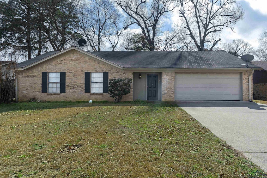 ranch-style house featuring a garage, a front yard, concrete driveway, and brick siding