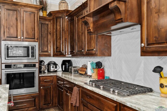 kitchen with decorative backsplash, light stone countertops, premium range hood, and stainless steel appliances