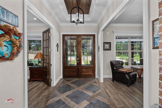 entryway featuring a chandelier, a raised ceiling, ornamental molding, and french doors