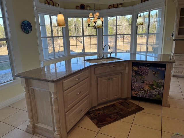 kitchen with sink, light tile patterned floors, black dishwasher, an island with sink, and a chandelier