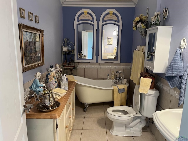 bathroom featuring tile patterned floors, a bathing tub, sink, toilet, and ornamental molding