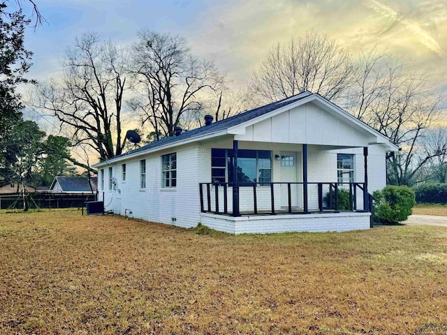 view of front of property with a porch, central AC unit, and a lawn