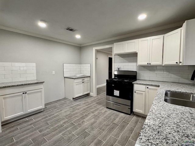 kitchen with sink, backsplash, light stone countertops, range with gas stovetop, and white cabinets