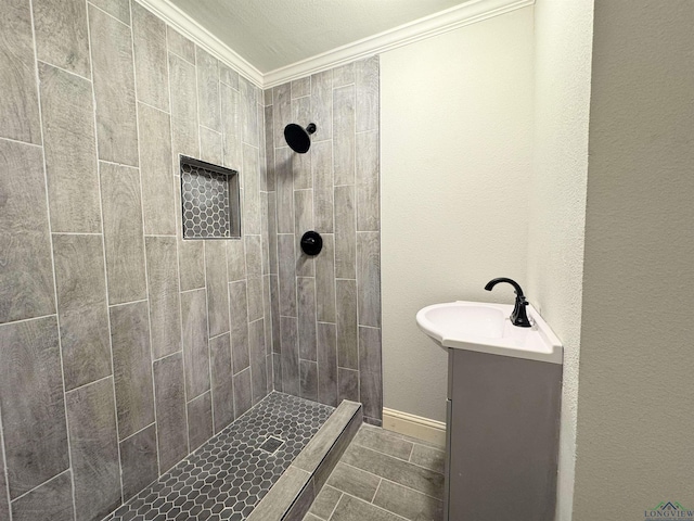 bathroom with vanity, crown molding, and a tile shower