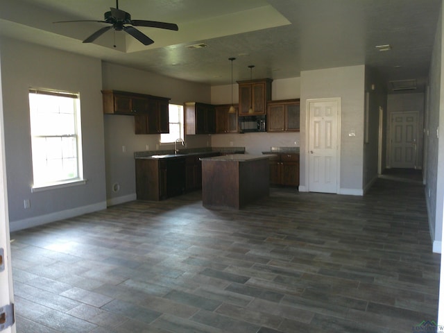 kitchen featuring sink, dark wood-type flooring, ceiling fan, hanging light fixtures, and a center island