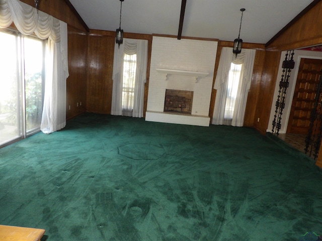 unfurnished living room featuring dark carpet, vaulted ceiling, a wealth of natural light, and wooden walls