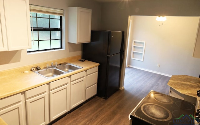 2104 Ark St, Marshall, TX 75670 - kitchen featuring dark wood finished floors, light countertops, freestanding refrigerator, and white cabinets