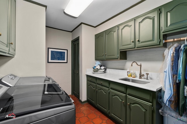 kitchen featuring washer and clothes dryer, dark tile patterned flooring, sink, green cabinetry, and ornamental molding