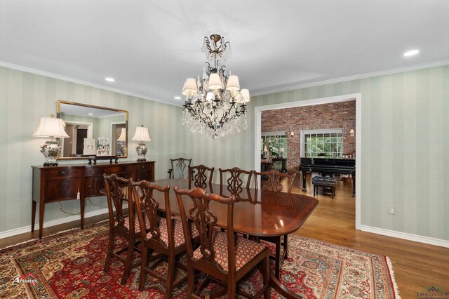 dining space with wood-type flooring, an inviting chandelier, and ornamental molding