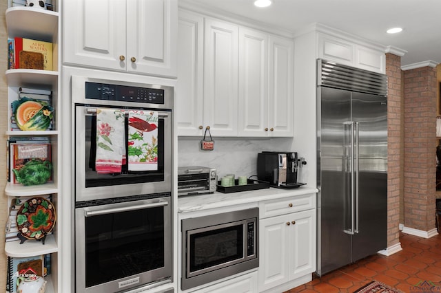 kitchen featuring built in appliances, white cabinetry, and dark tile patterned flooring