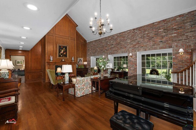 interior space with high vaulted ceiling, brick wall, dark hardwood / wood-style floors, a notable chandelier, and ornamental molding