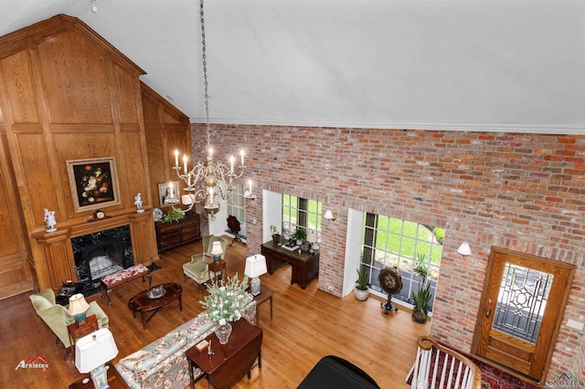 living room featuring a high end fireplace, wood-type flooring, brick wall, and an inviting chandelier