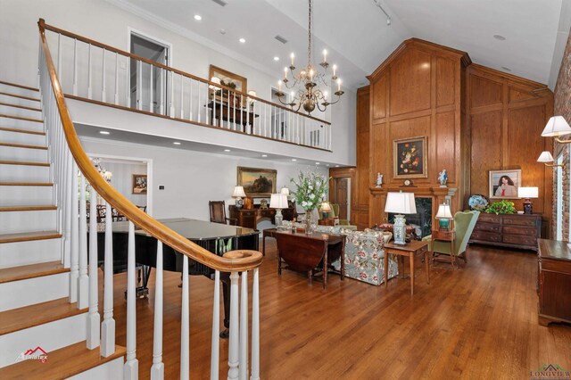 interior space with wooden walls, crown molding, high vaulted ceiling, a chandelier, and dark hardwood / wood-style floors