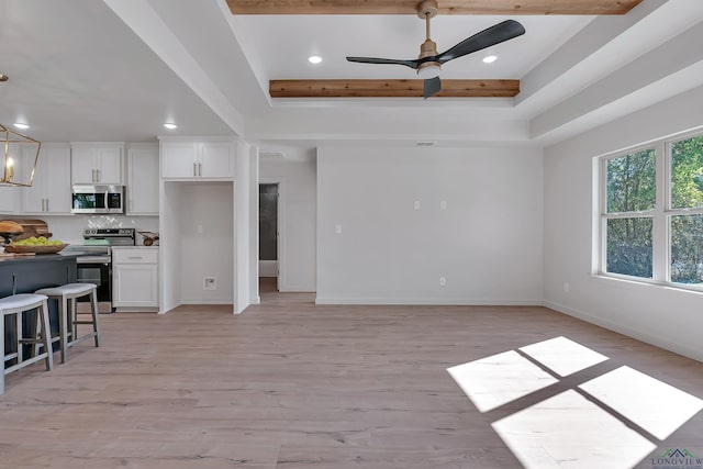 unfurnished living room with a tray ceiling, ceiling fan, and light hardwood / wood-style floors