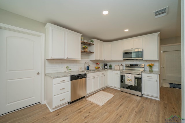 1021 N Montgomery St, Gilmer, TX 75644 - kitchen with appliances with stainless steel finishes, open shelves, light wood-type flooring, white cabinetry, and recessed lighting