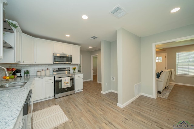 1021 N Montgomery St, Gilmer, TX 75644 - kitchen featuring stainless steel appliances, tasteful backsplash, white cabinetry, light wood-type flooring, and recessed lighting