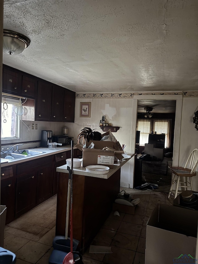 kitchen with dark brown cabinets, sink, a wealth of natural light, and a textured ceiling