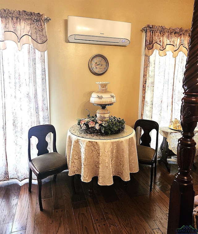 dining space with a wall mounted air conditioner and hardwood / wood-style flooring