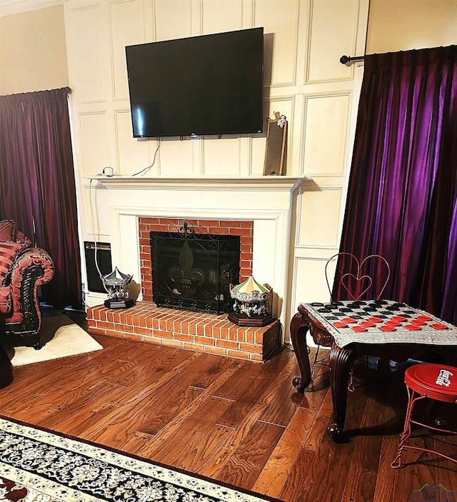 living room featuring wood-type flooring and a brick fireplace