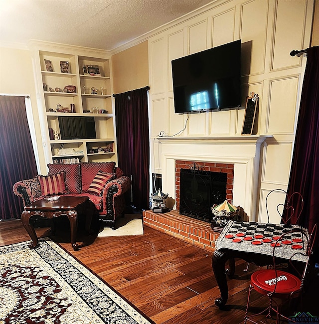 living room with wood-type flooring, crown molding, and a brick fireplace