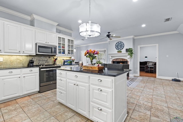 5201 Whitaker, Longview, TX 75605 - kitchen featuring stainless steel appliances, dark countertops, a brick fireplace, ornamental molding, and a ceiling fan
