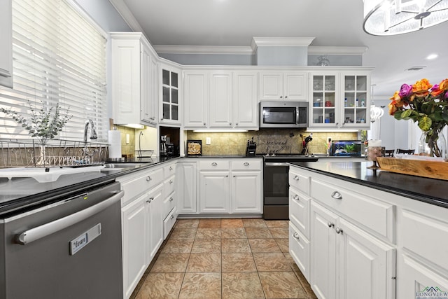 5201 Whitaker, Longview, TX 75605 - kitchen featuring appliances with stainless steel finishes, dark countertops, crown molding, backsplash, and white cabinets