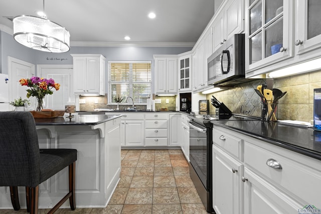 5201 Whitaker, Longview, TX 75605 - kitchen with black range with electric cooktop, stainless steel microwave, ornamental molding, dark countertops, and white cabinets