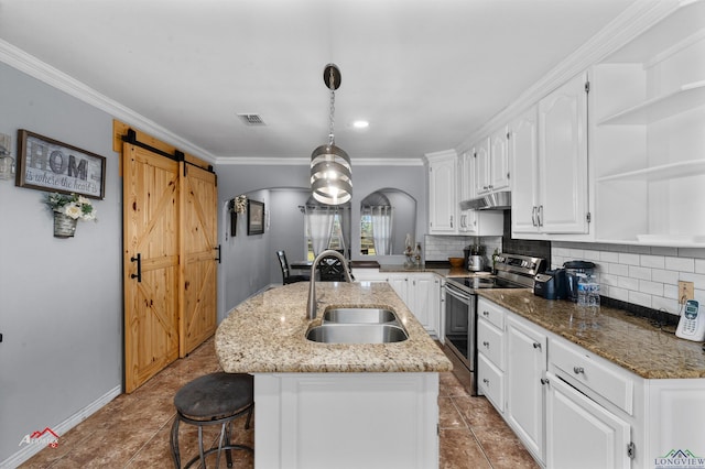 kitchen with stainless steel range with electric cooktop, a kitchen island with sink, sink, a barn door, and white cabinetry