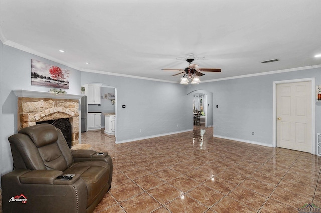 living room with tile patterned floors, a stone fireplace, ceiling fan, and ornamental molding