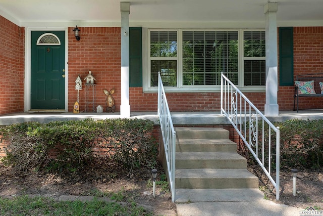 property entrance with a porch and brick siding