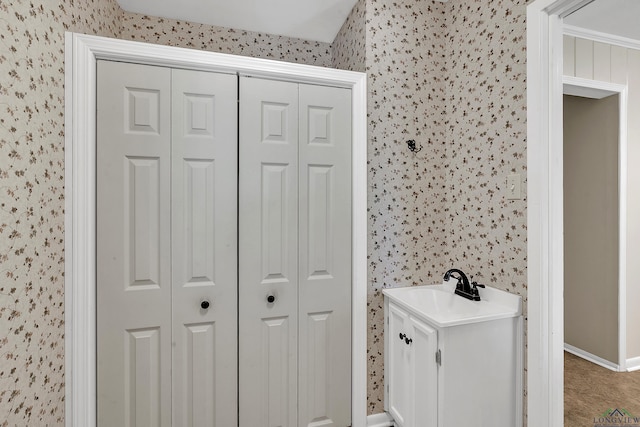 bathroom featuring baseboards, wallpapered walls, and a closet