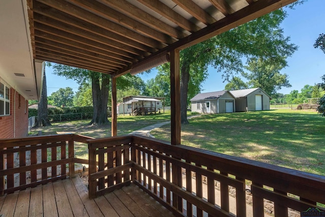 wooden terrace with fence, a lawn, and an outdoor structure