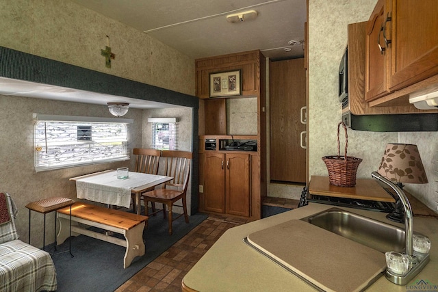 kitchen featuring brown cabinets, brick patterned floor, and a sink