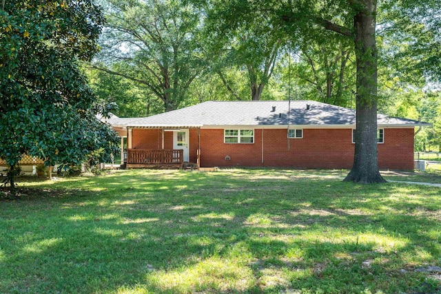 rear view of house featuring brick siding and a lawn