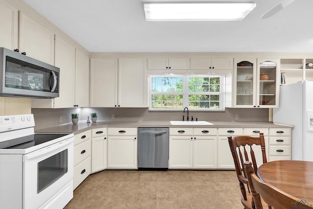 kitchen with glass insert cabinets, white cabinetry, stainless steel appliances, and a sink