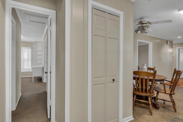 hall featuring crown molding, baseboards, and light colored carpet