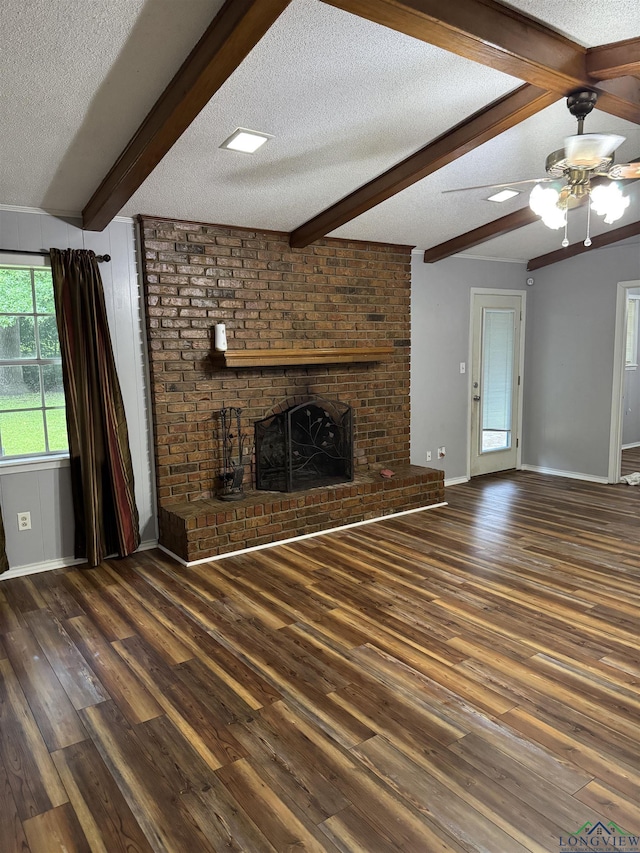 909 Stewart St, Atlanta, TX 75551 - unfurnished living room with a textured ceiling, hardwood / wood-style flooring, beam ceiling, a fireplace, and ceiling fan